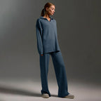Side view of model wearing a steel blue oversized polo jumper and matching wide leg knit trousers