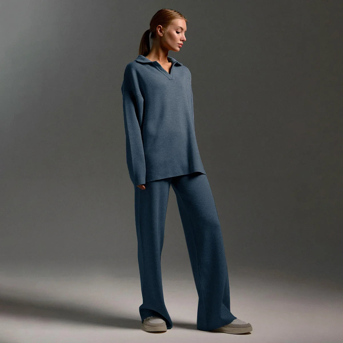 Side view of model wearing a steel blue oversized polo jumper and matching wide leg knit trousers