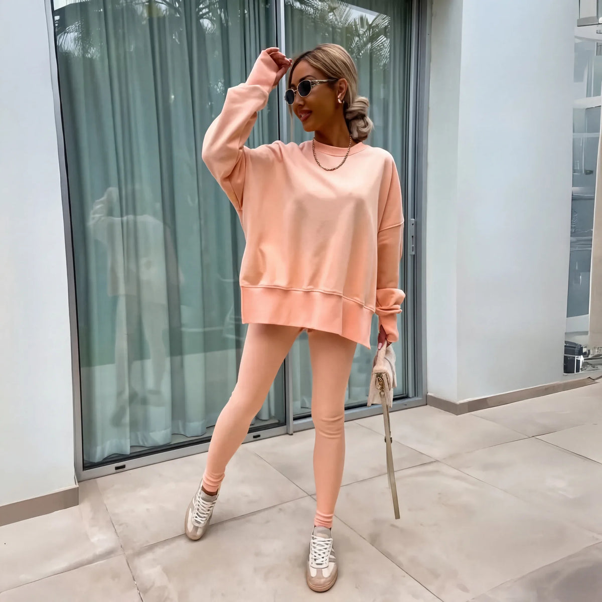 Peach coloured oversized sweatshirt and matching leggings styled with white trainers and a small bag