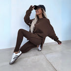 Chocolate brown ribbed leggings and matching oversized sweatshirt shown in a seated pose with trainers