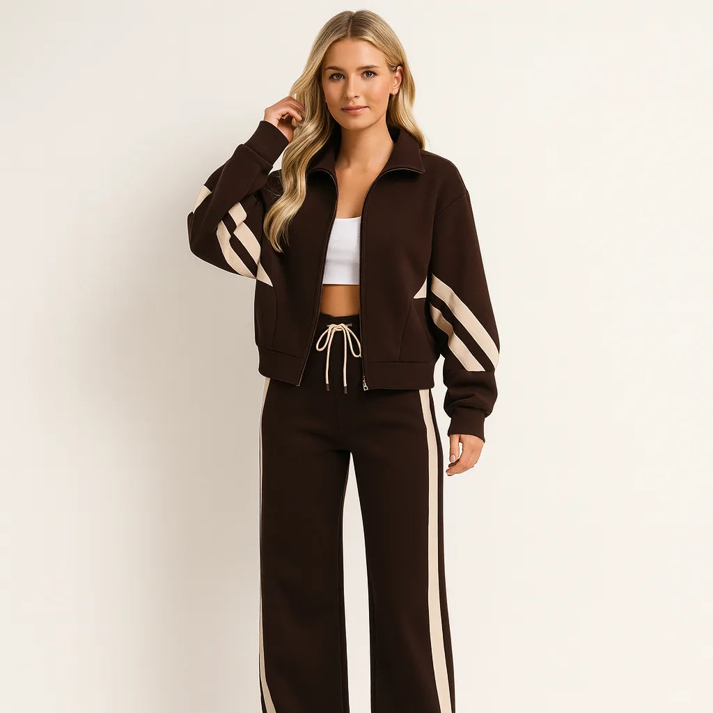 Woman wearing a brown zip-up tracksuit jacket with cream diagonal stripes and matching wide-leg brown joggers