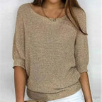 Close-up front view of beige knitted jumper with scoop neckline, gold necklace and batwing sleeves