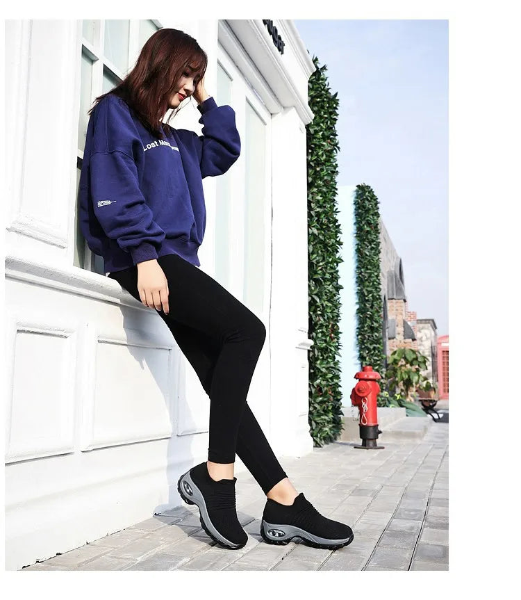 Rear angle of black slip-on trainers showing the ribbed ankle cuff and chunky tread sole