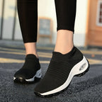 Front view of black knitted slip-on trainers with white platform sole worn with black leggings