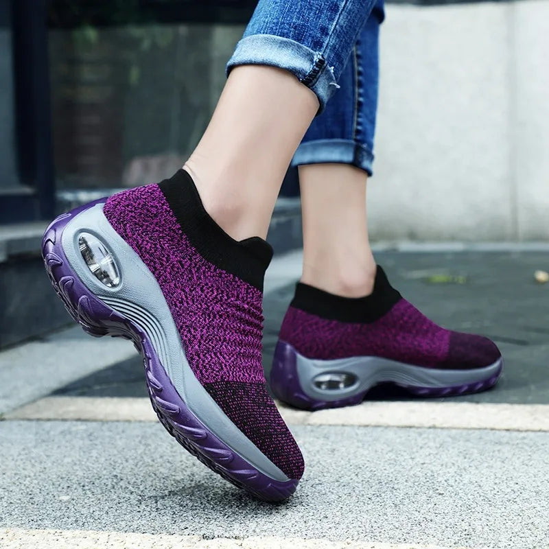 Grey and black marled knit slip-on trainers worn walking on a paved street