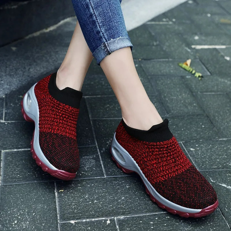 Purple and black knitted sock trainers with grey platform sole and visible air cushion in the heel