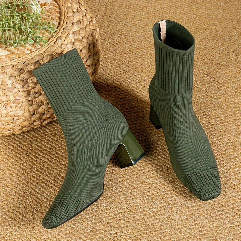 Olive green knit sock boots with glossy block heel, shown side by side on a natural fibre rug