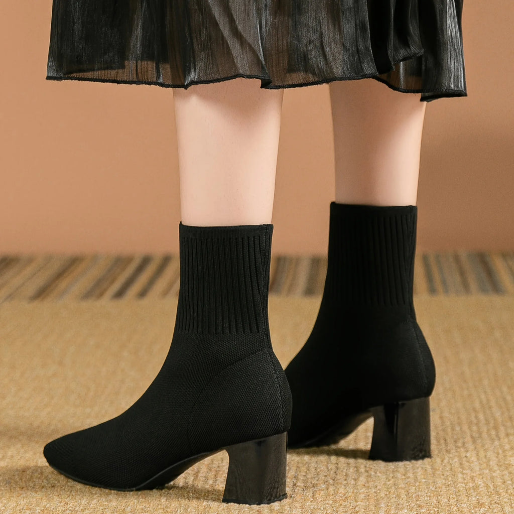 Back view of model's ankles in black knitted sock boots, highlighting the ribbed knit collar and heel shape