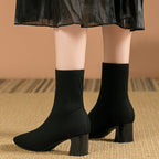 Back view of model's ankles in black knitted sock boots, highlighting the ribbed knit collar and heel shape