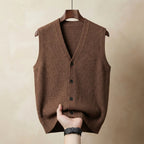 Brown ribbed-knit waistcoat with dark buttons, hand pulling the hem to show drape and knit texture