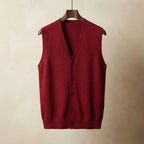Burgundy red knitted waistcoat with V-neck and button-up front, hanging flat against a warm backdrop