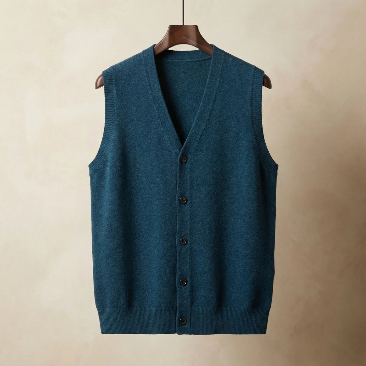 Teal blue knitted waistcoat with button-up front, displayed hanging against a neutral studio background