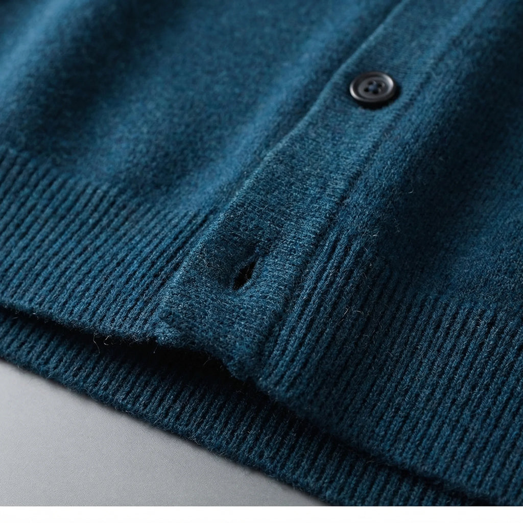 Close-up of teal knitted fabric showing the buttonhole, ribbed hem and soft knit texture in detail