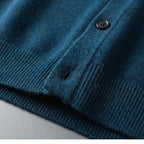 Close-up of teal knitted fabric showing the buttonhole, ribbed hem and soft knit texture in detail