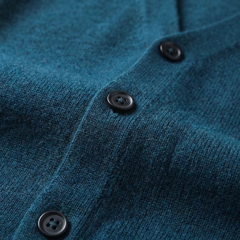 Close-up view of the button placket and ribbed side seam on a teal knitted waistcoat