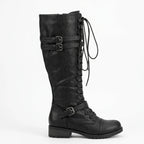 Side view of a black knee-high lace-up combat boot with double buckle straps and lug sole