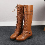 Tan lace-up knee-high boots displayed standing on a grey floor, showing full front lacing and buckles.