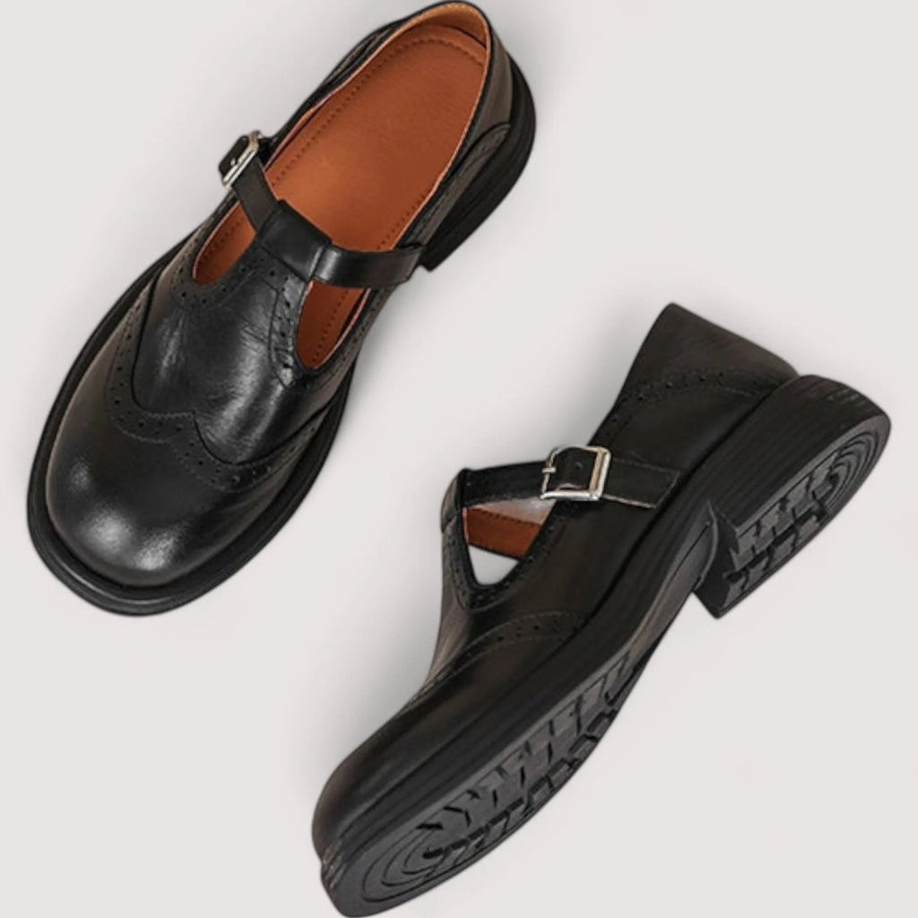 Top-down view of black leather Mary Jane shoes showing the buckle fastening and brogue punch-hole pattern