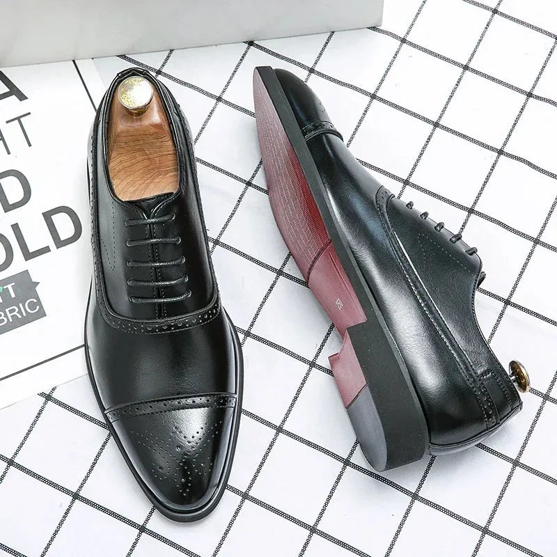 Pair of glossy black brogue oxford shoes with wooden shoe trees, one shoe turned to show the burgundy sole
