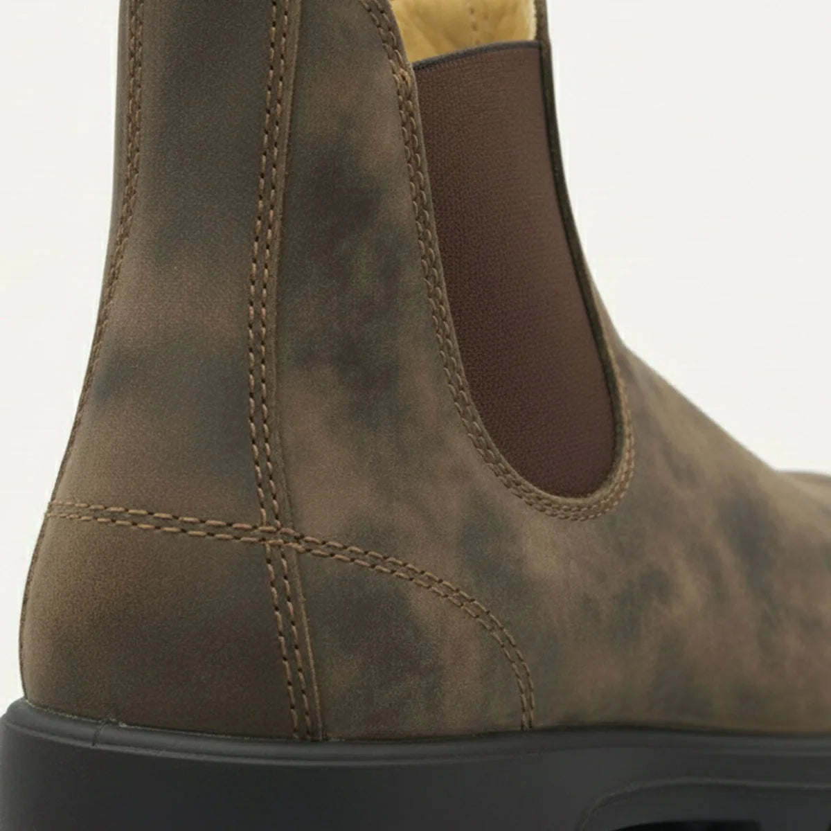 Close-up of the heel and elastic gusset on a weathered brown leather Chelsea boot