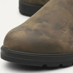 Detail shot of the rounded toe and tread sole on a distressed brown leather Chelsea boot