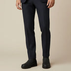 Close-up of a man's legs in navy pinstripe trousers rolled above black Chelsea boots