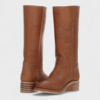 Front-angled view of tan brown leather knee-high boots with square toe and multi-layer stacked wooden heel