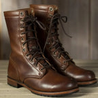 Side view of dark brown leather lace-up boots with mid-calf shaft and metal eyelets on wooden floorboards