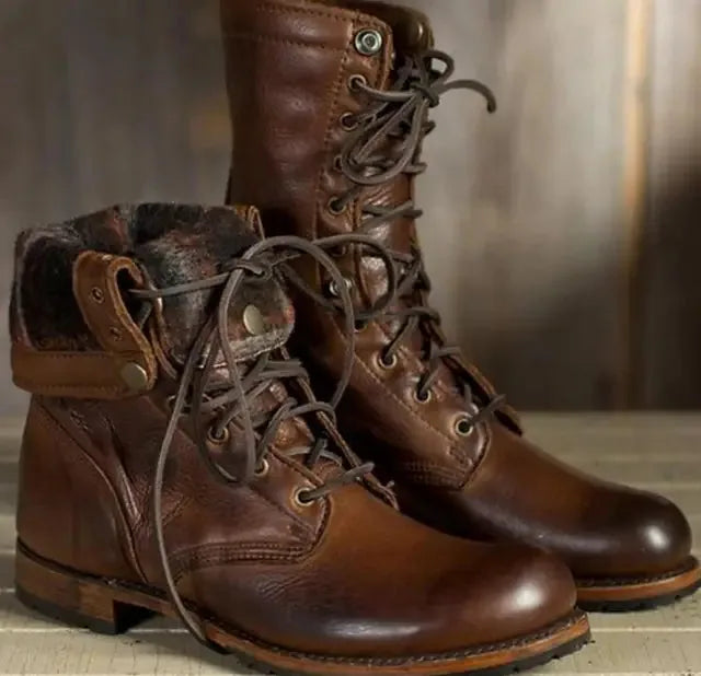 Close-up of dark brown leather boots with a fold-down cuff, checked lining and brass-tone press studs