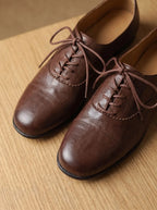 Flat lay of a pair of tan leather oxford shoes with ribbed cream and brown socks tucked inside