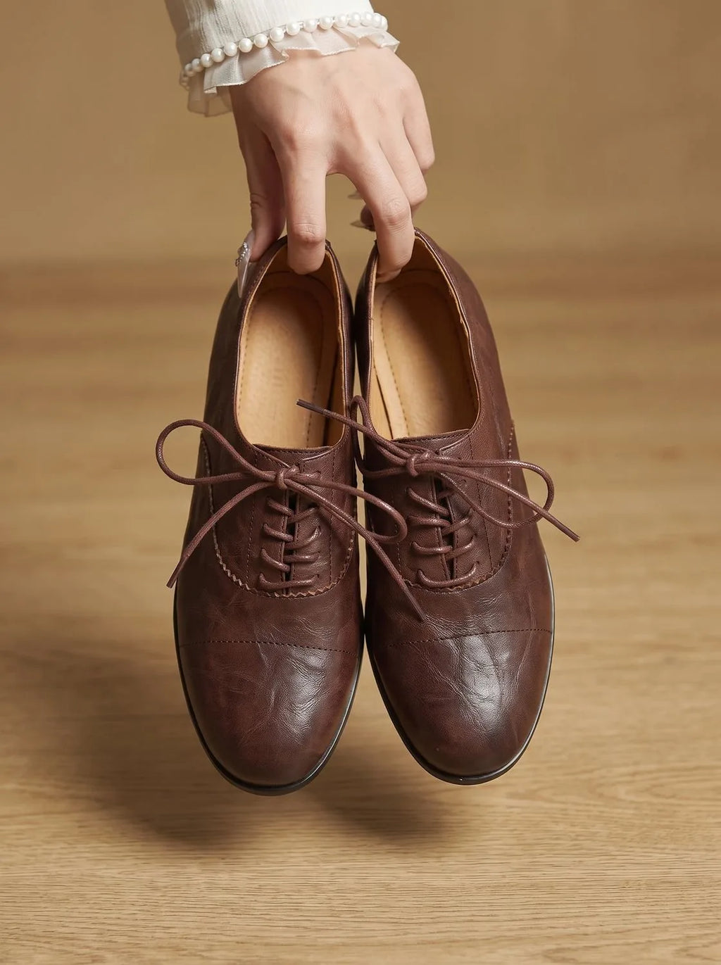 Side angle close-up of a tan leather oxford shoe showing stitched cap-toe and lace-up vamp detail