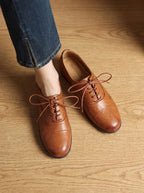 Overhead view of two tan leather lace-up oxfords with cap-toe stitching and tied laces, Handmade branded insole visible