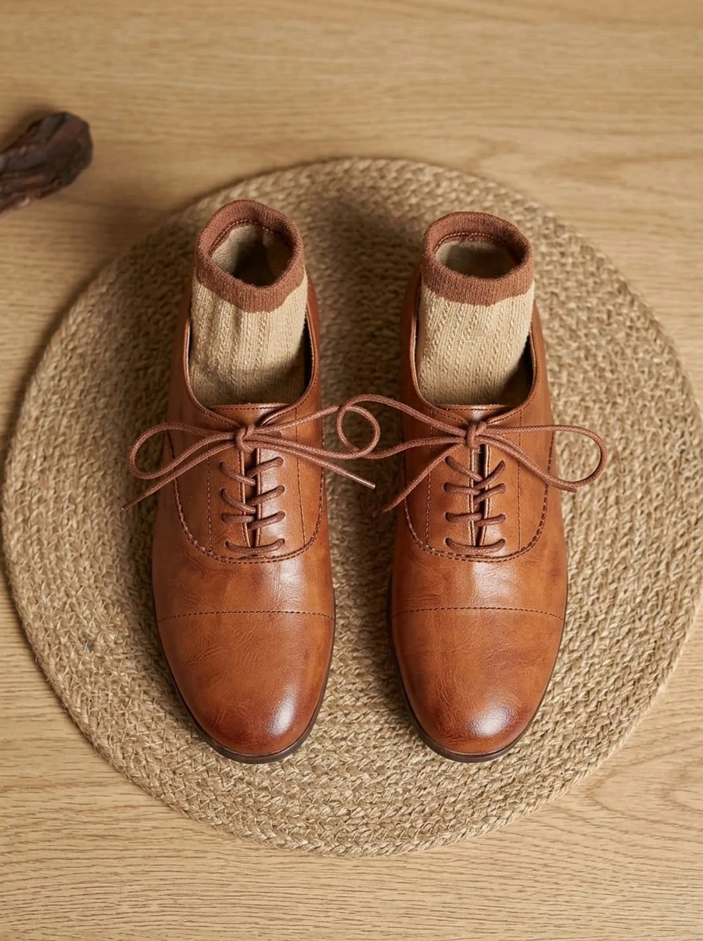 Overhead view of a pair of tan leather oxford shoes with Lane Male branded insole, placed on wooden table
