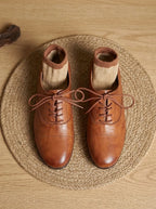 Overhead view of a pair of tan leather oxford shoes with Lane Male branded insole, placed on wooden table