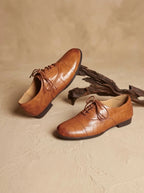 Top-down view of tan leather oxford shoes with laces tied in bows, resting on a round woven jute mat