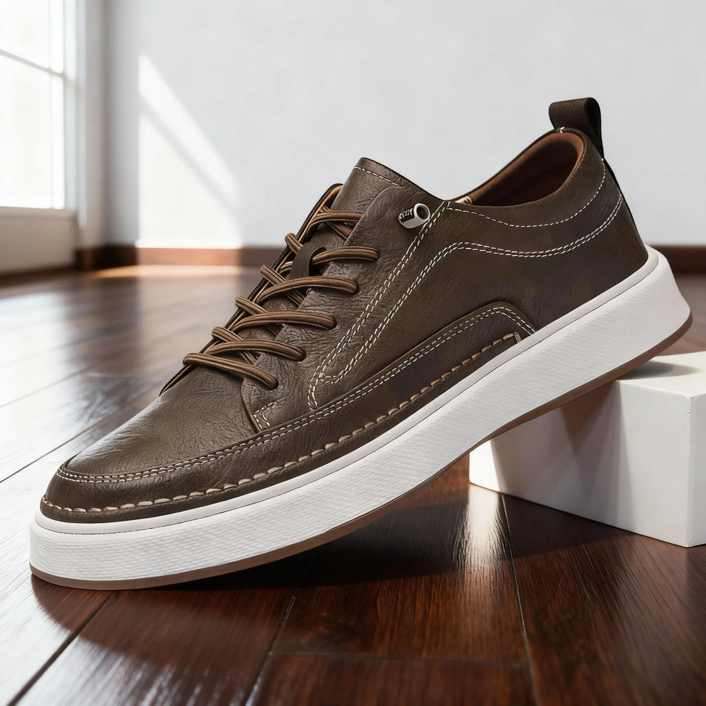 Side view of khaki brown leather trainer showing contrast stitching and white cupsole, resting against a white block