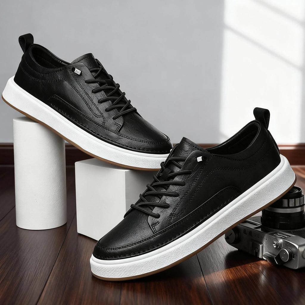 Pair of black leather trainers with lace detail and gum soles styled beside a vintage camera on wooden flooring