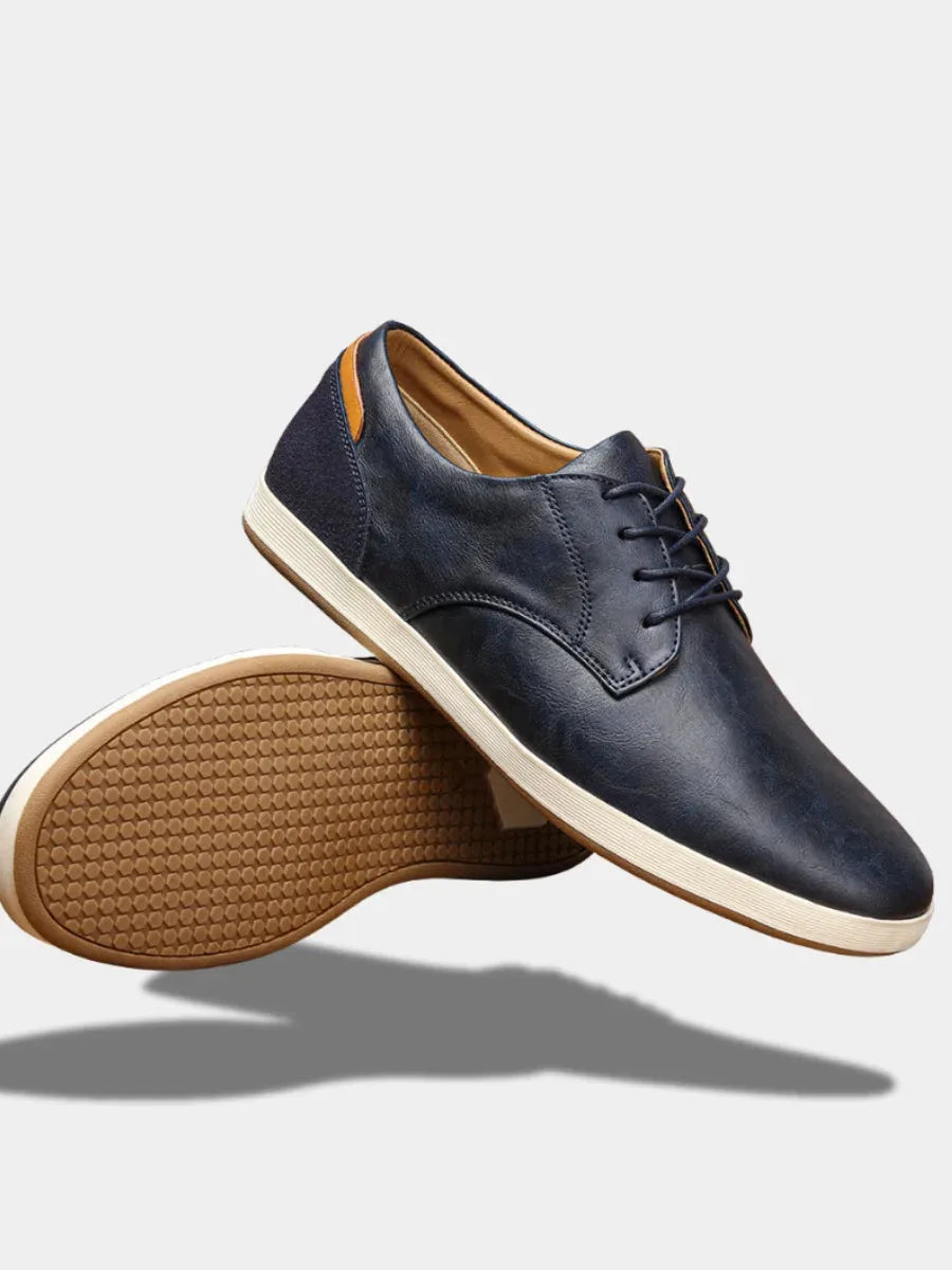 Navy leather lace-up trainer shown from a top-down angle with ribbed white and tan outsole and tan insole
