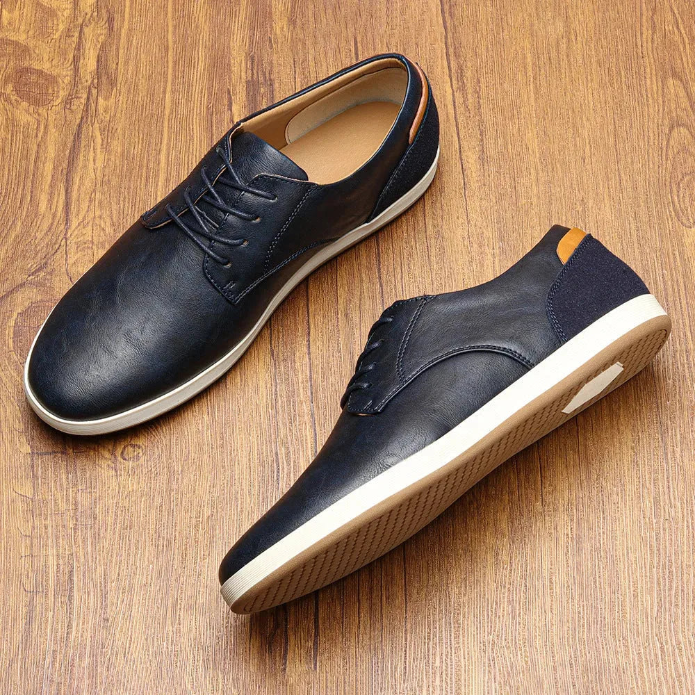 Navy leather trainer on plain white background showing lace-up front, rounded toe and white rubber sole