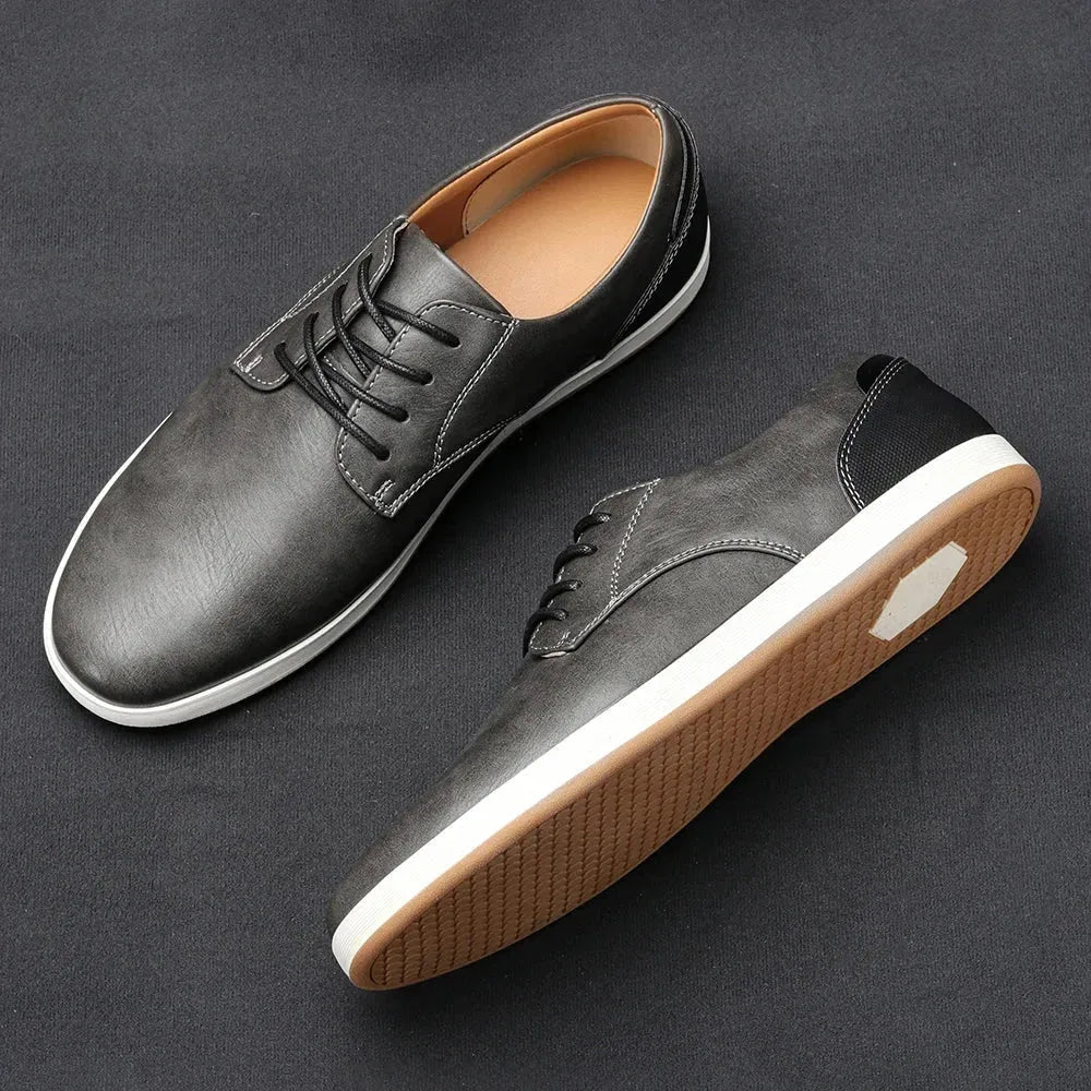 Overhead view of tan brown leather lace-up trainer beside its sole showing tread pattern and white rim