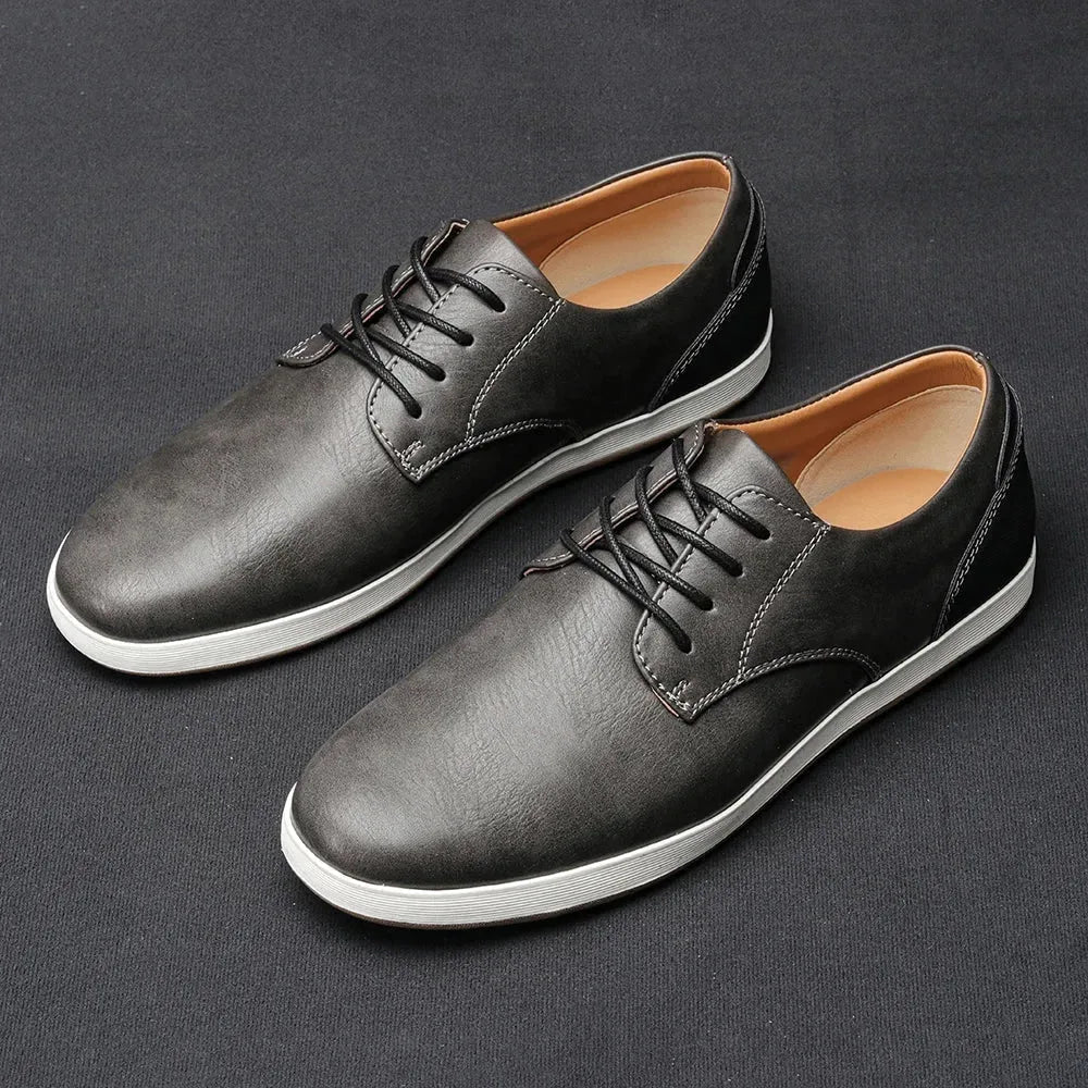 Pair of dark brown leather lace-up trainers with black heel counter displayed on a dark grey backdrop
