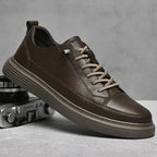 Black leather trainer held in a hand, showing the ridged outsole and side profile