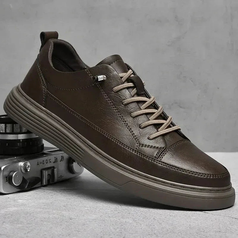 Black leather trainer held in a hand, showing the ridged outsole and side profile