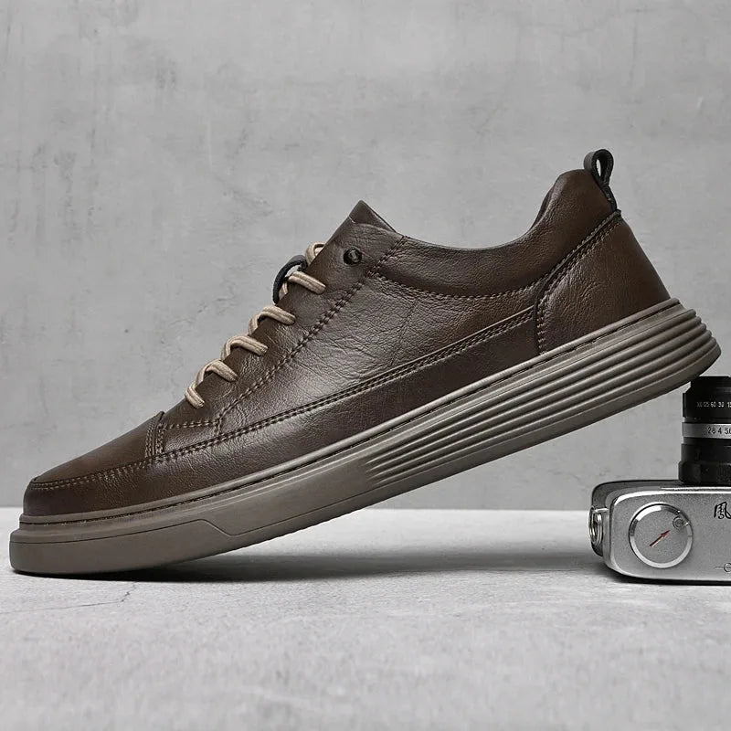Black leather trainer on a grey background showing the pull tab at the heel