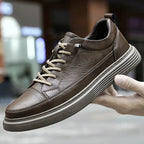 Side view of a black leather trainer resting on textured concrete flooring