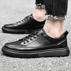 Side view of a brown leather lace-up trainer with contrast stitching worn with dark trousers