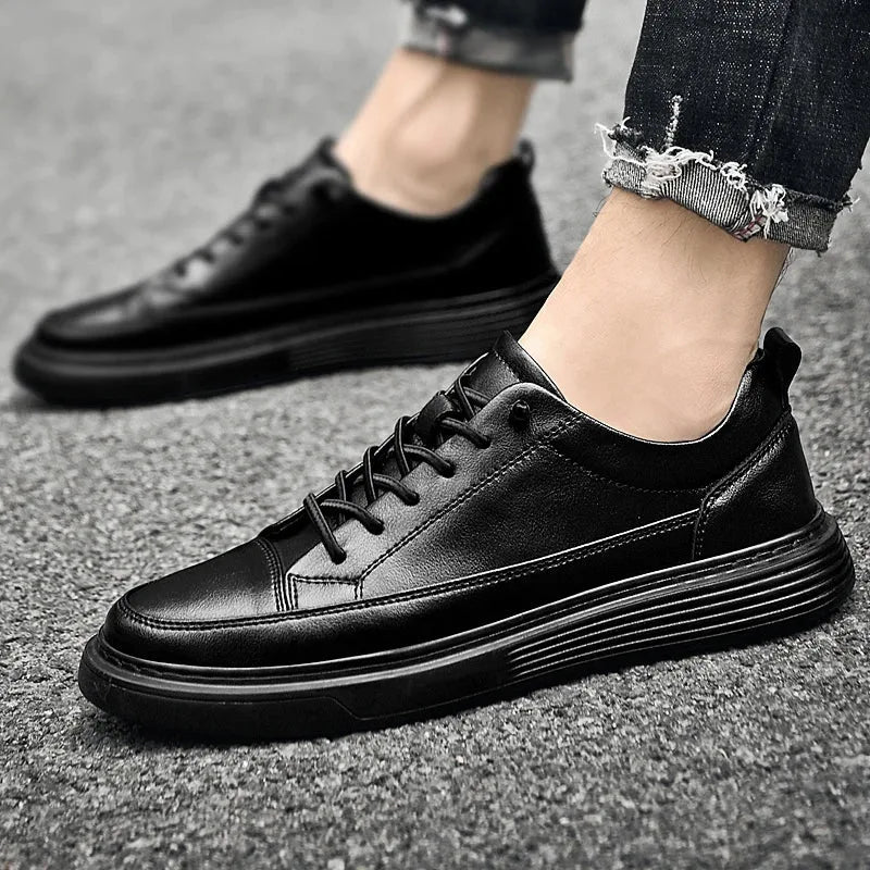 Angled close-up of a black leather trainer showing the rounded toe and tonal stitched panels