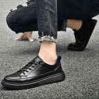 Black leather trainer worn with ripped black jeans, cropped view of the ankle and shoe