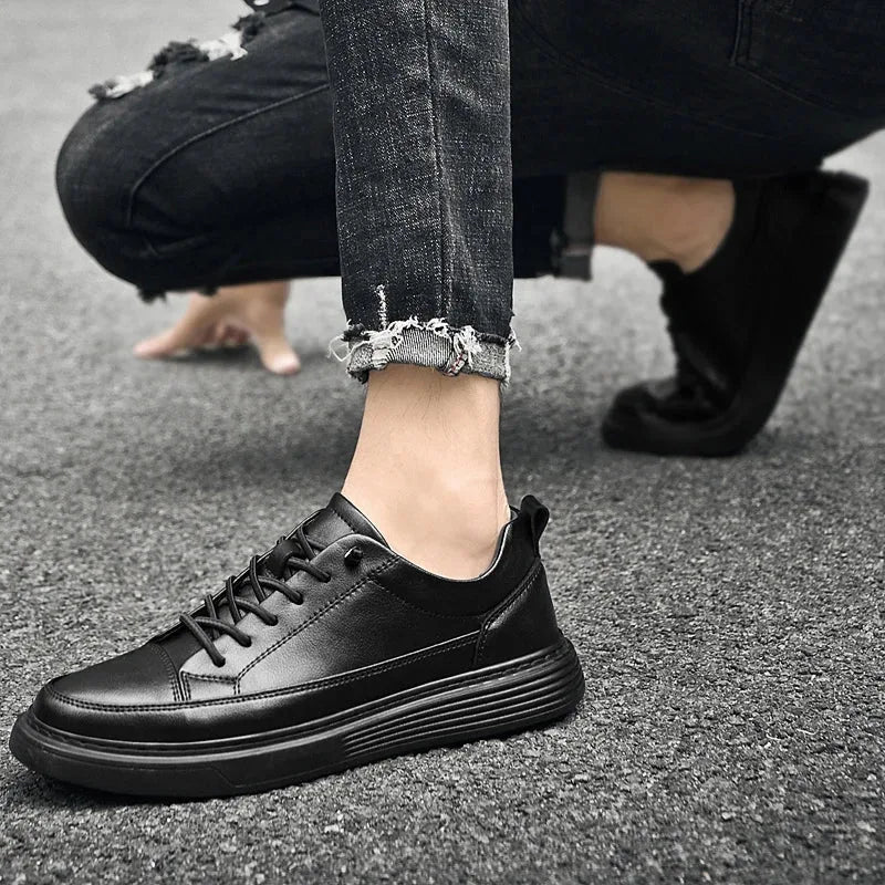 Black leather trainer worn with ripped black jeans, cropped view of the ankle and shoe