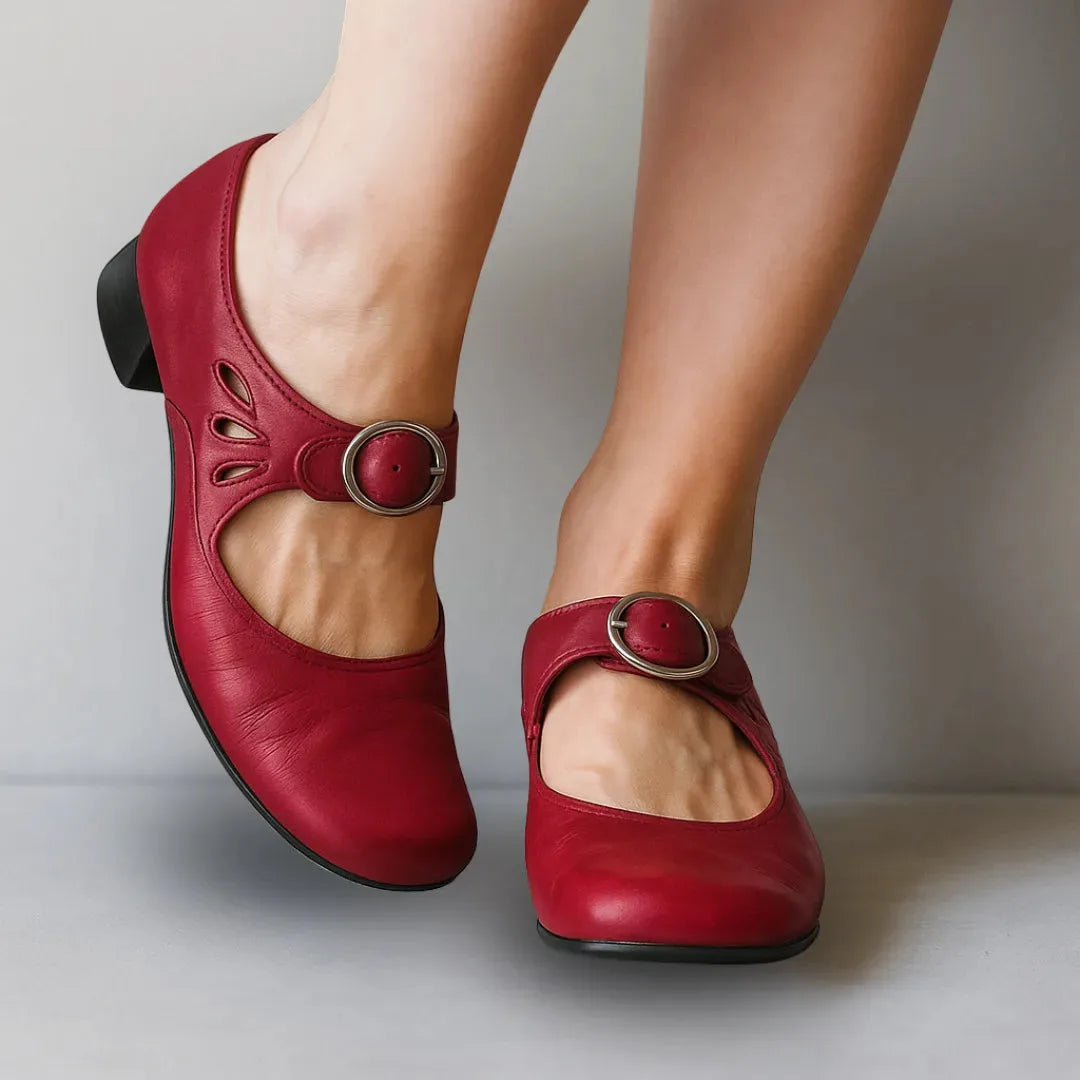 Deep red leather Mary Jane flats with round toe, silver buckle strap and decorative cut-outs, side angle view